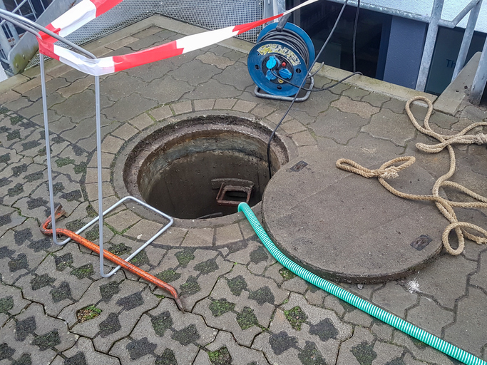 drain with a cctv camera doing an inspection and safety tape around the manhole cover. 